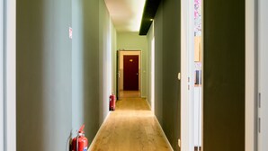 A hallway with wooden flooring, light green walls, and a red door at the end. - Leuhusen Center Apartments Vienna (Vienna)
