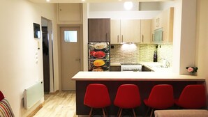 Une cuisine compacte dotée d’un îlot central, de meubles en bois et d’un revêtement mural moderne.