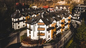 A multi-story residential building with a central courtyard, balconies, and a mix of white and brown exteriors. - Apartamenty Forma Tatrica (Zakopane)
