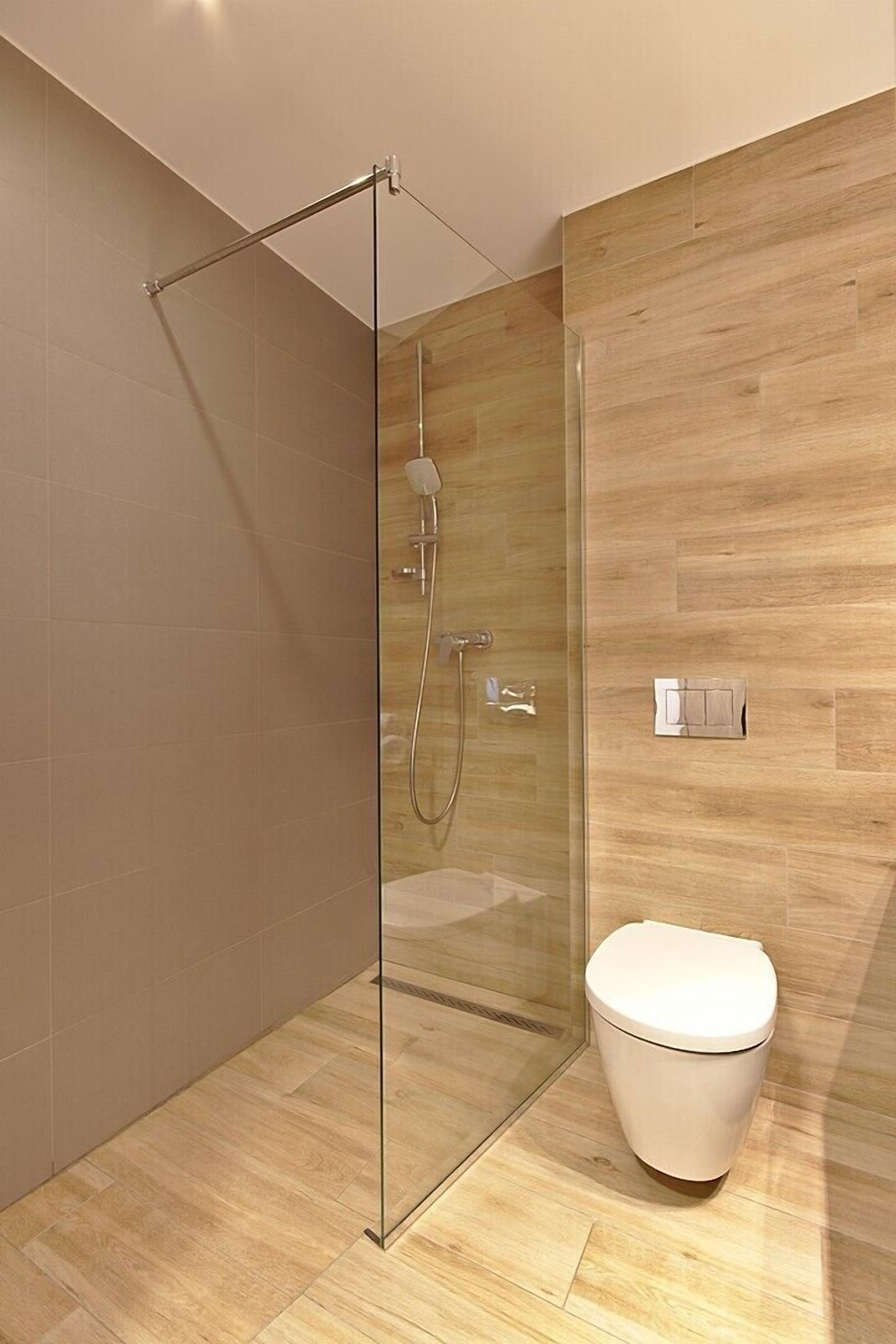 Un baño moderno con cabina de ducha de vidrio, un inodoro y una pared de madera.