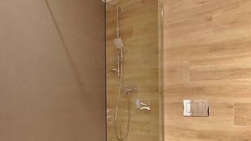 Un baño moderno con cabina de ducha de vidrio, un inodoro y una pared de madera.