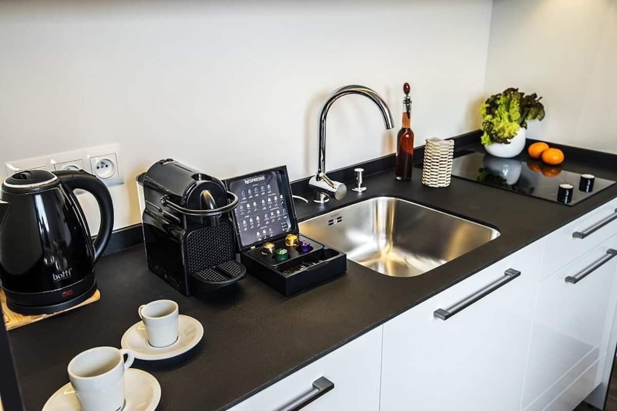 Una cocina moderna con cafetera, máquina de espresso y un lavamanos.