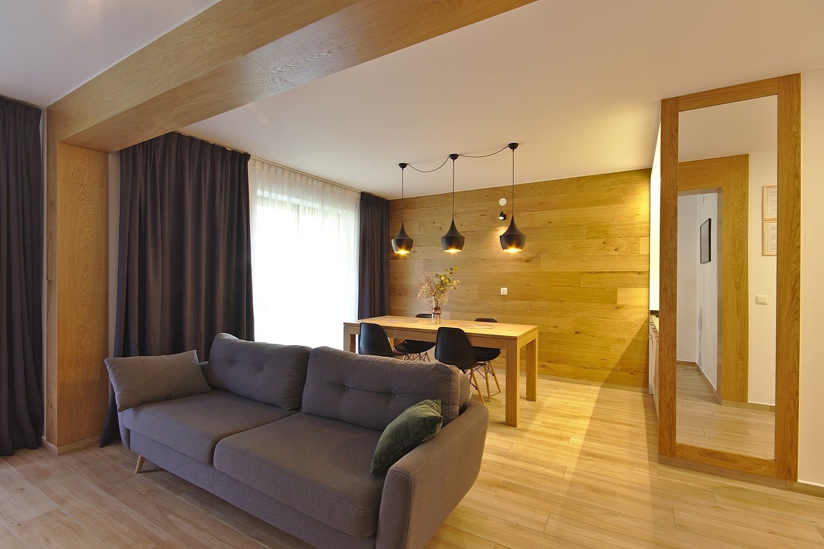 Ein modernes Wohnzimmer mit einer Couch, einem Esstisch und Pendelleuchten.