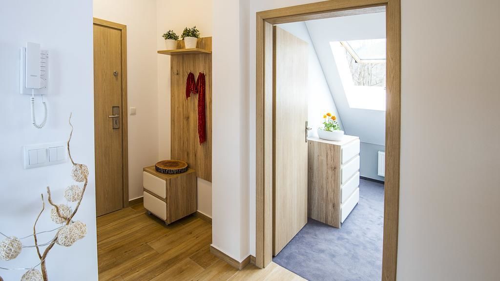 A modern bedroom with a wooden wardrobe, a small bedside table, and a window with a view.
