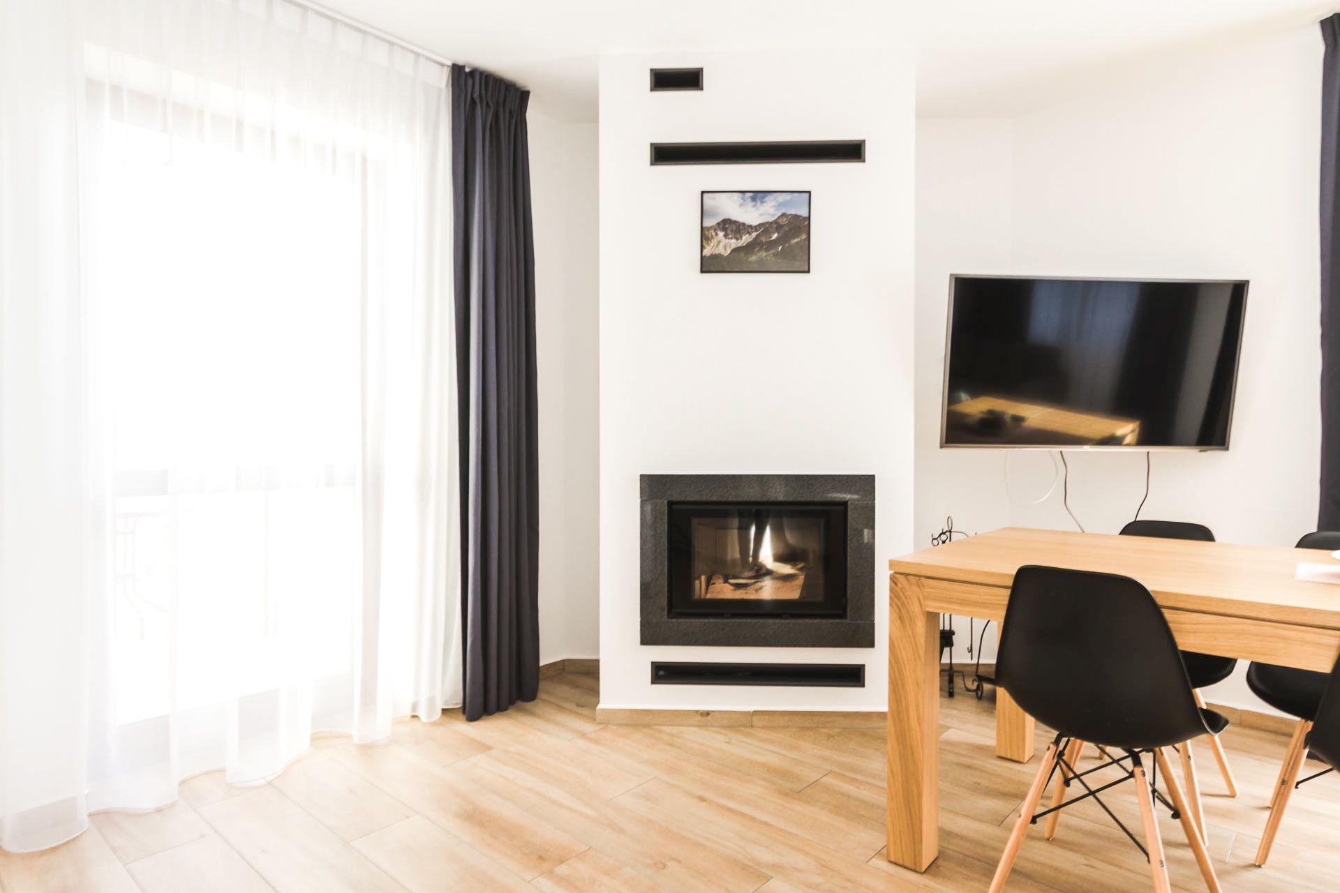 Uma sala de estar moderna com lareira, uma mesa de jantar e uma televisão de tela plana.