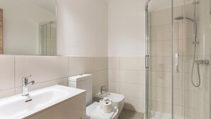 A modern bathroom with a glass-enclosed shower, a white sink, and a toilet. - Girasole (Savosa)