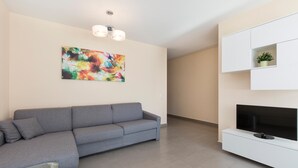 A modern living room with a grey sofa, a flat-screen TV, and a colorful abstract painting on the wall. - Girasole (Savosa)