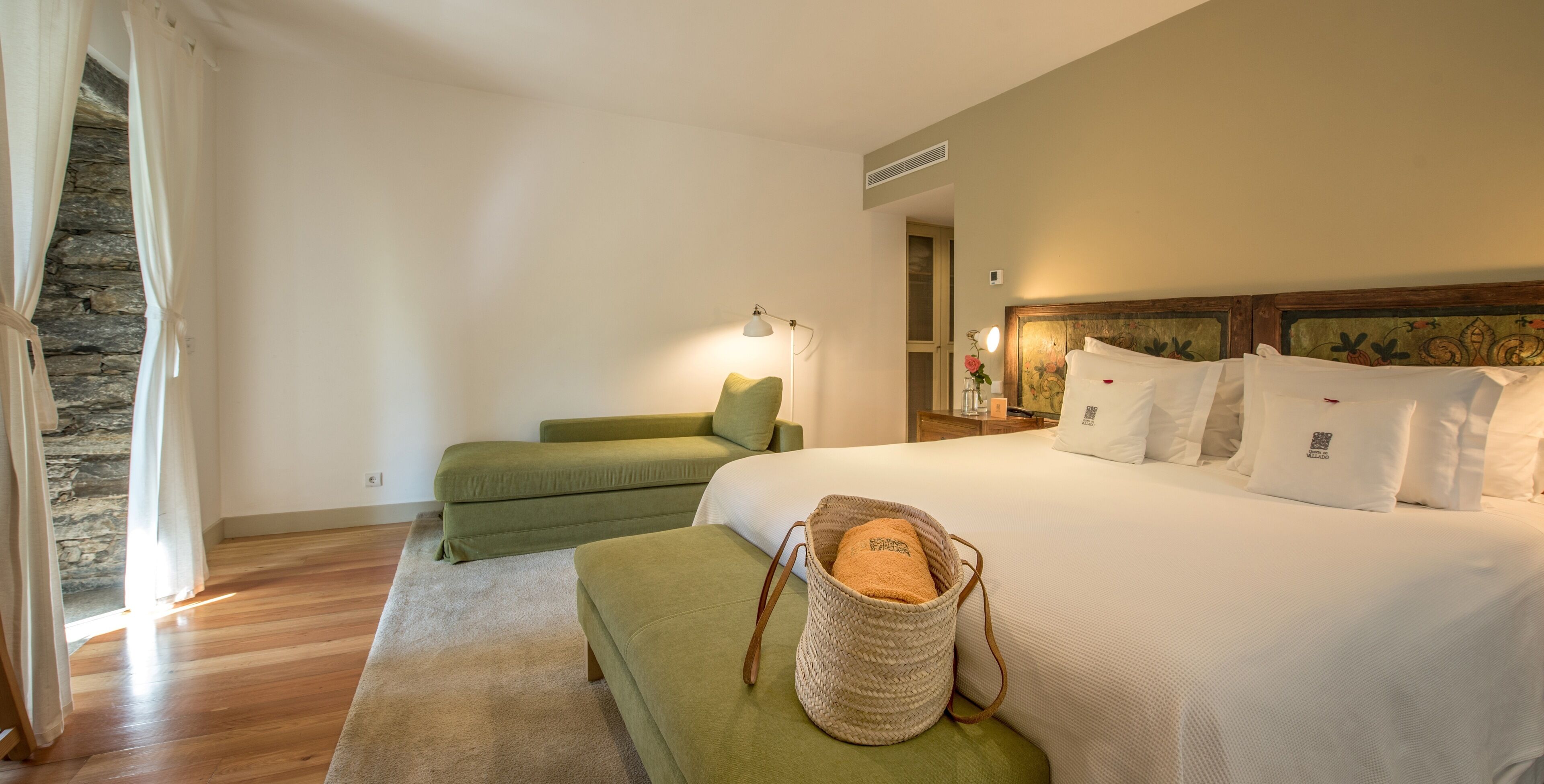 Ein Hotelzimmer mit einem Bett, einem grünen Sofa, einem Korbwäscheschrank und einer Steinwand.