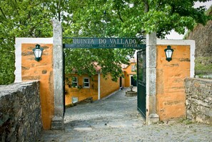 A cobblestone street leading to a building with a sign reading "QUINTA DO VALLADO."