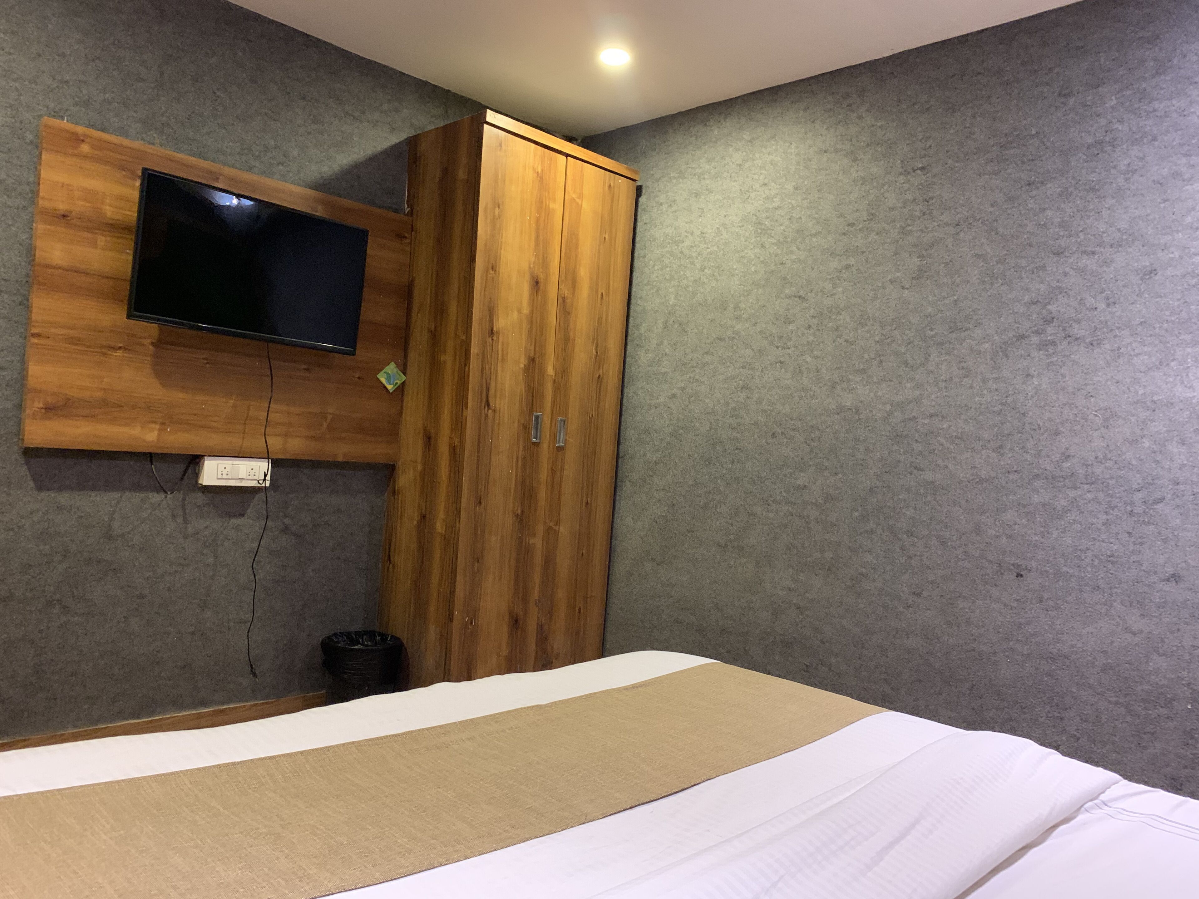Ein Schlafzimmer mit einem Bett, einem Holzschrank und einem an der Wand befestigten Fernseher.