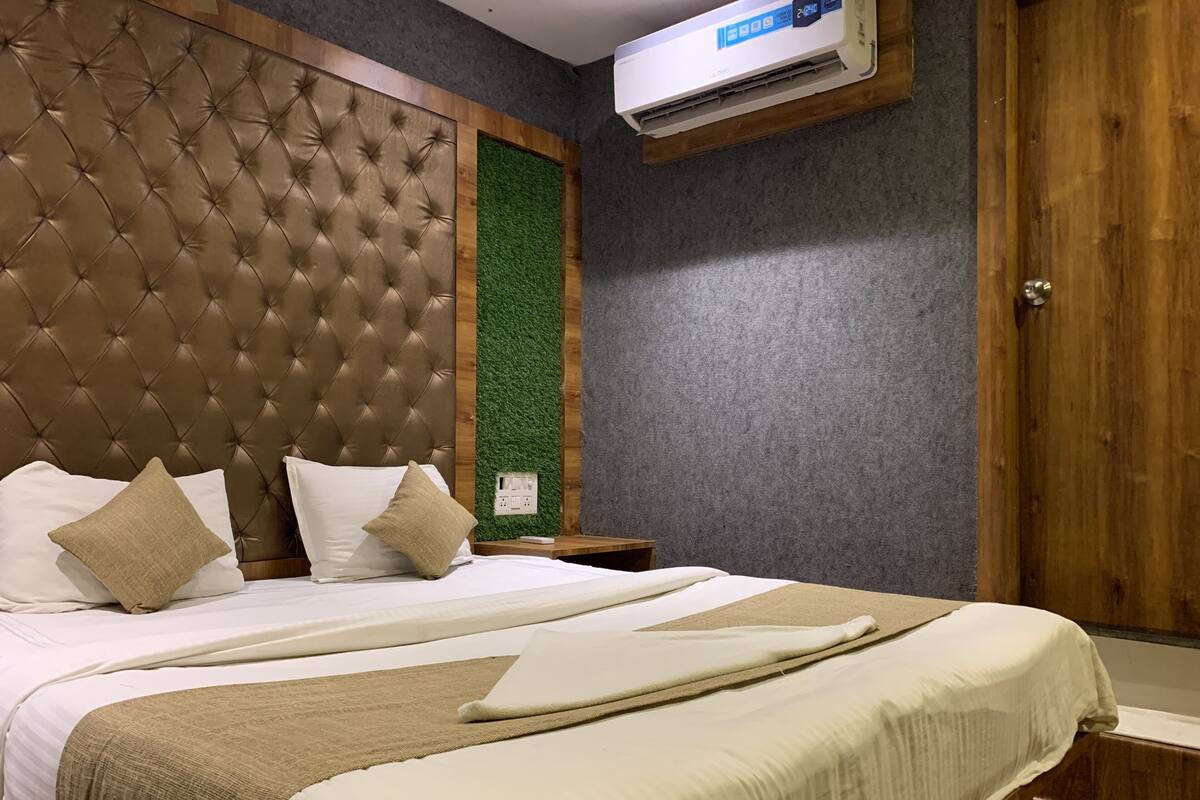 A hotel room with a tufted headboard, a green vertical accent wall, and a wooden door.