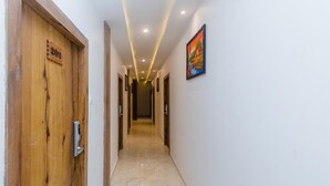 A hallway with wooden doors, numbered 202, and a painting on the wall. - Hotel Riva International - Near Nesco Center (Mumbai)