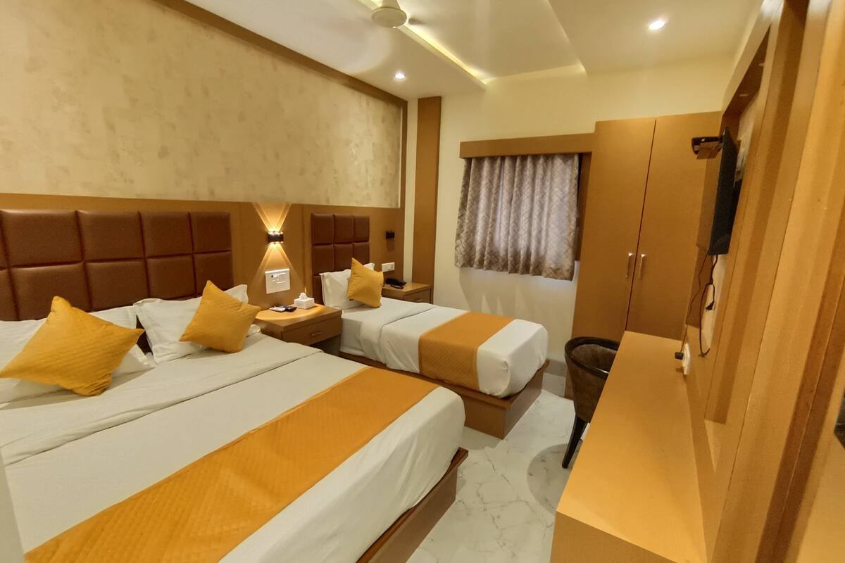 A hotel room with two beds, a wardrobe, a vanity, and a window with curtains.