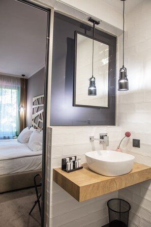 A modern bathroom with a white sink, wooden countertop, and a large mirror. - Reverence Hotel (Varna)