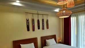 Una habitación de hotel con dos camas, una lámpara de pared y una ventana con cortinas.