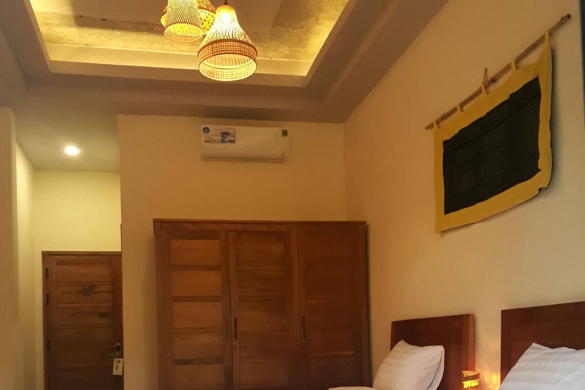 Une chambre à coucher avec un grand lit, une armoire en bois et un luminaire fixé au plafond.