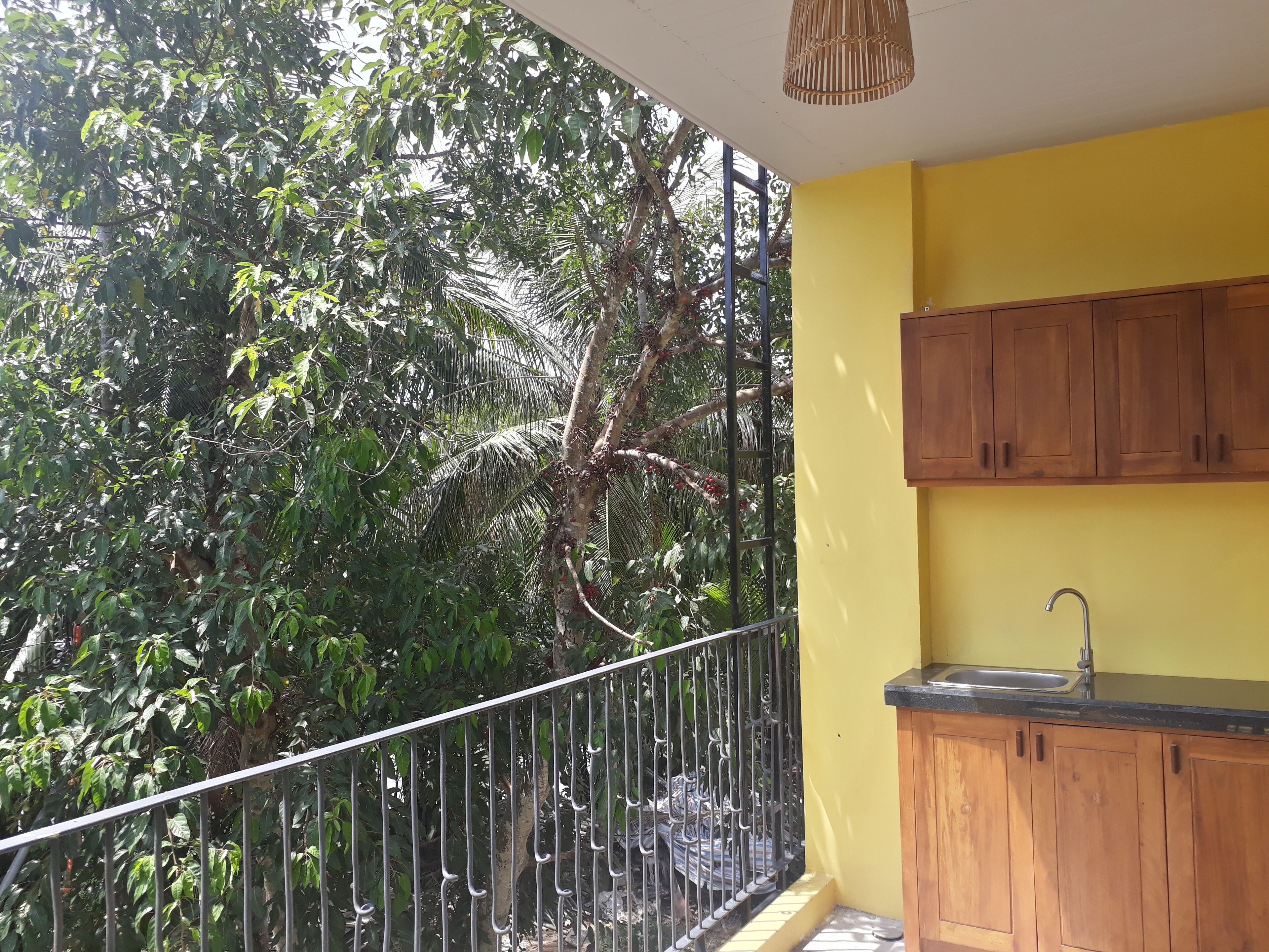 Un balcon avec une balustrade en métal, un mur jaune et des armoires en bois.