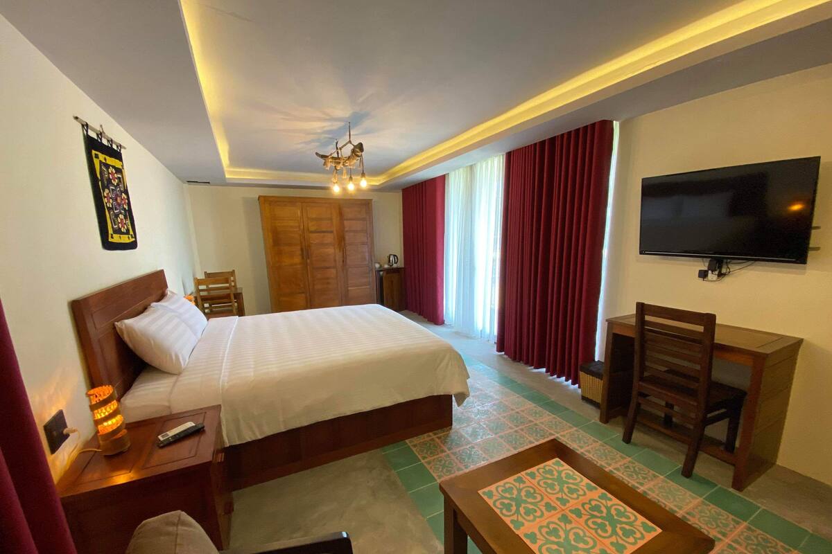 Une chambre d’hôtel avec un lit, un bureau, une télévision, une chaise et une table.