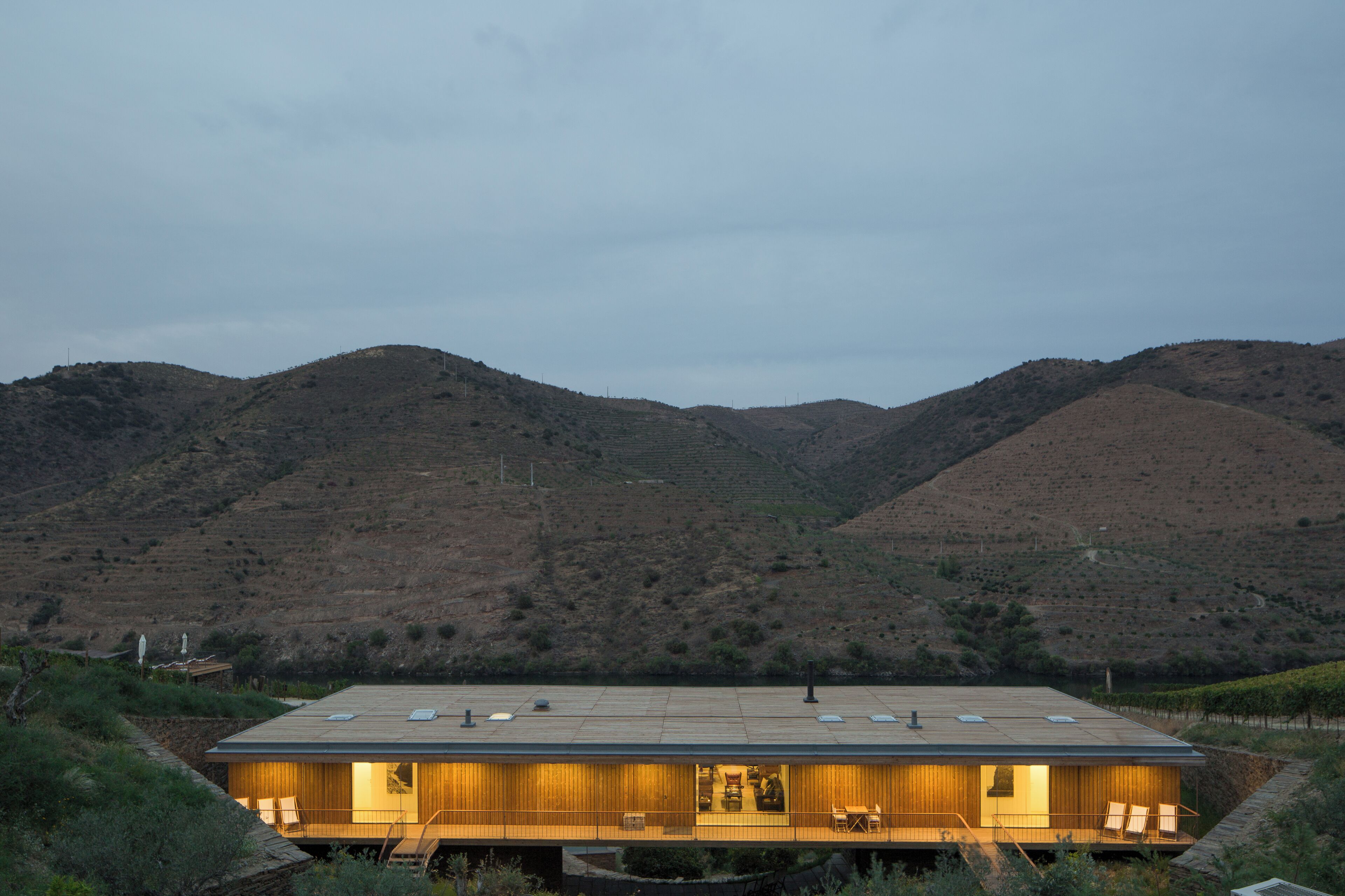 A modern building with a flat roof, large windows, and a flat terrace with outdoor seating.