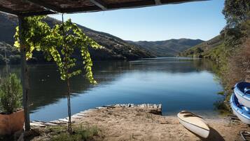A covered dock with a canoe and a kayak, overlooking a calm lake with hills in the background.