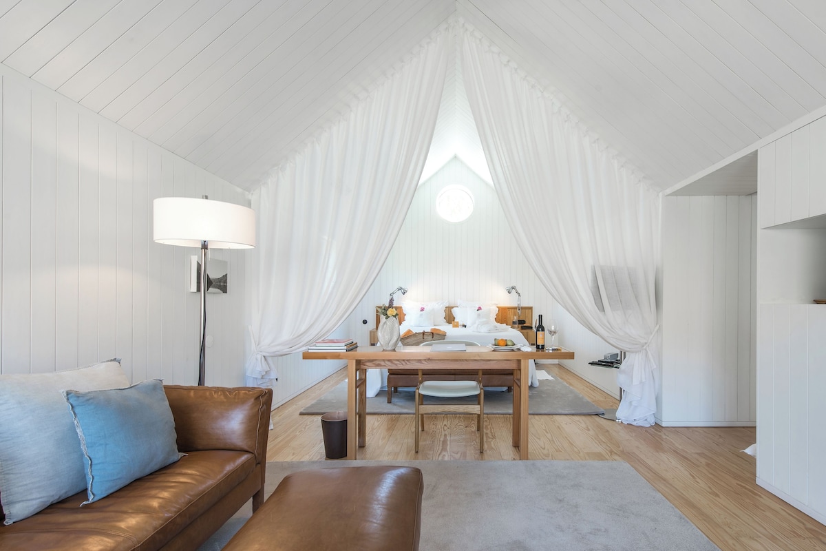 Una habitación acogedora con una cama, un escritorio de madera, una lámpara y una chimenea.