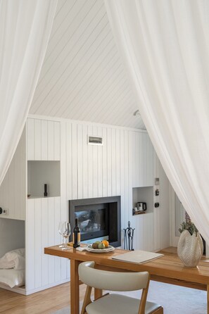 A cozy dining area with a wooden table, a chair, a television, and a white wall with built-in shelves.