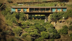 Un edificio moderno con tejado plano, ventanas amplias y un balcón con mobiliario exterior.