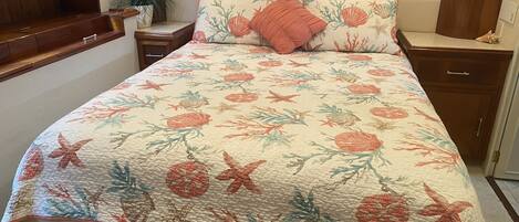 Ein Schlafzimmer mit einer floralen Steude, einem Holzkopfende, Nachttischen und einem Beistelltisch mit einer Pflanze.