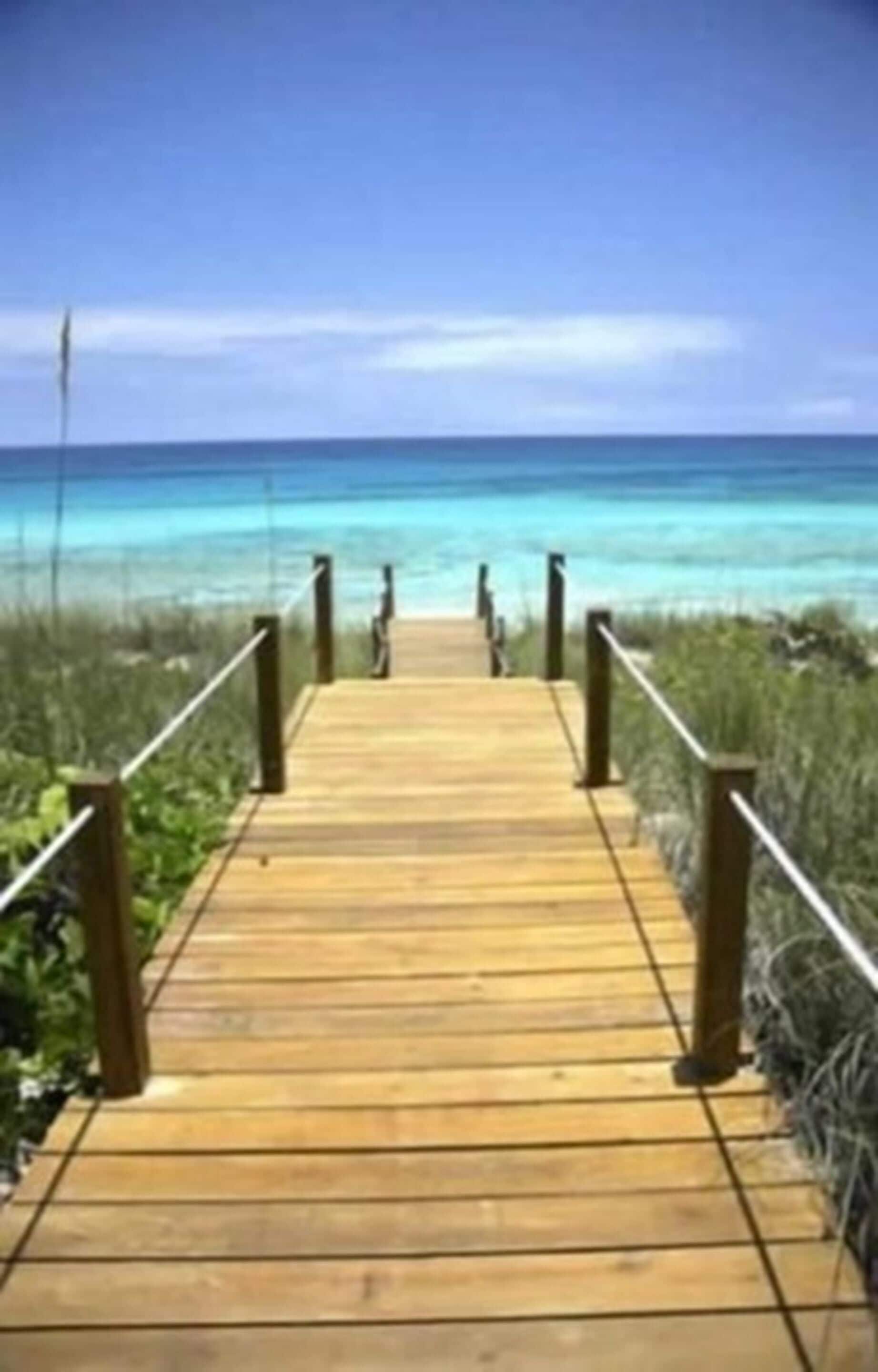Una passera de fusta que condueix a una platja d'aigua turquesa cristal·lina.