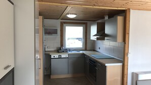 A compact kitchen with a microwave, stove, and sink. - Kleines Ferienhaus (Berlin)