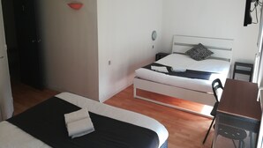 Une chambre avec deux lits, un bureau et une petite table.