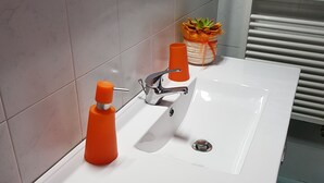 A bathroom with a white sink, a chrome faucet, and two orange soap dispensers. - Ca' del Sol Venezia (Venice)