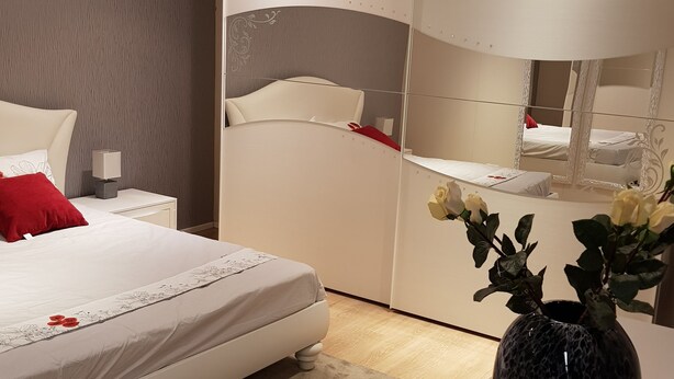 A bedroom with a bed, a nightstand, a mirror, and a vase with flowers. - Ca' del Sol Venezia (Venice)