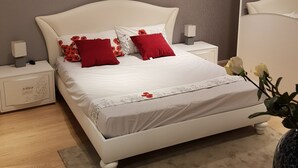 A modern bedroom with a large bed, two nightstands, a bedside table, and a vase with flowers. - Ca' del Sol Venezia (Venice)