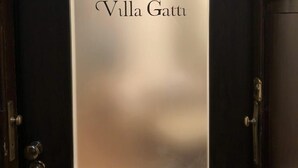 A door with a frosted glass panel displaying the logo and name "Villa Gatti". - Villa Gatti (Milan)