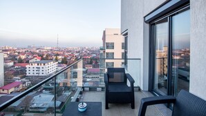 Un balcón con vistas a la ciudad, con dos sillas de mimbre y una mesita.