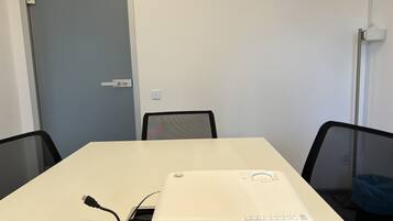 A conference room with a white table, black chairs, and a projector on the table.