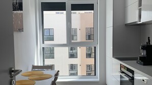 Una cocina moderna con armarios blancos, una mesa de comedor con sillas y un ventanal con vistas al exterior.