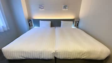 A double bed with two pillows, a headboard with a light fixture, and a small wall decoration.