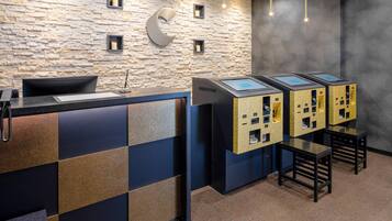 Un'area reception con parete in pietra, una scrivania moderna e postazioni self-service.