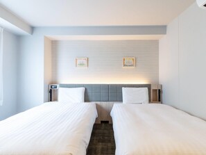 Una habitación de hotel con dos camas individuales, un cabecero con panel de luz y dos cuadros en la pared.
