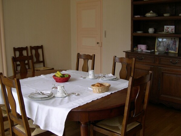 A dining table set with white tablecloth, wooden chairs, and a fruit basket. - Les Chambres du Chapitre (Langres)