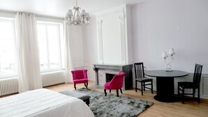 Una habitación de hotel con cama, chimenea, una mesa de comedor con sillas y un candelabro.