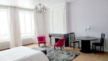 Una habitación de hotel con cama, chimenea, una mesa de comedor con sillas y un candelabro.
