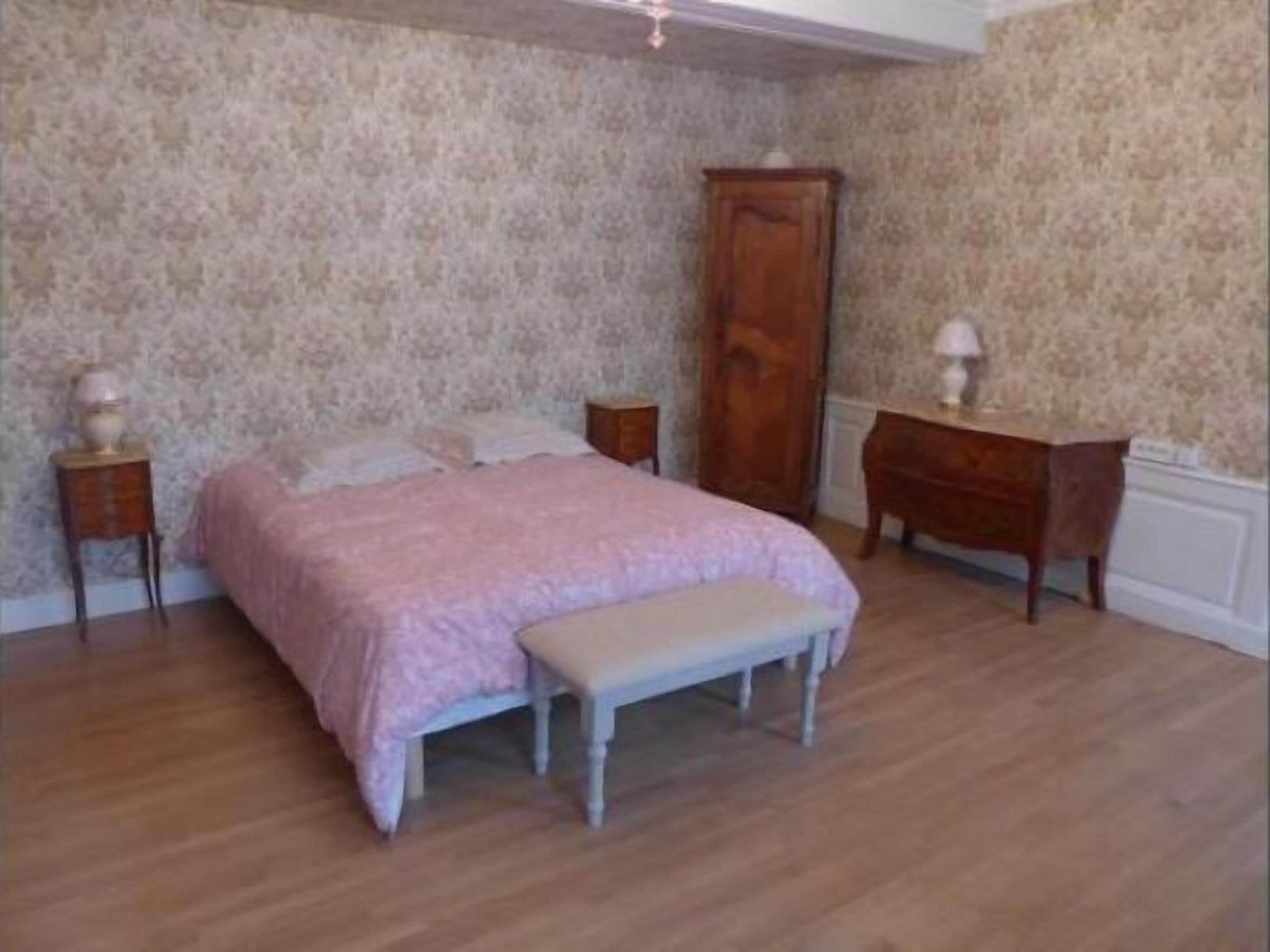 A bedroom with a bed, a nightstand, a dresser, and a bench.