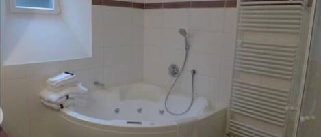 A bathroom with a freestanding bathtub, a towel rack, and a towel dispenser.