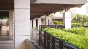 A covered outdoor area with stone pillars, a metal railing, and green landscaping. - Life Resort Hplus Long Stay (Brasília)