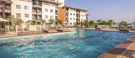 Una piscina al aire libre, sillones reclinables de piscina