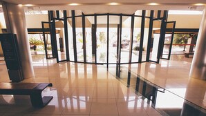 A lobby with a glass partition, a bench, and a signboard. - Life Resort Hplus Long Stay (Brasília)