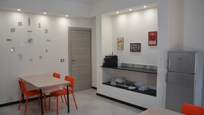 A modern kitchen with a dining table, chairs, a refrigerator, and wall-mounted clocks. - Casa dei Nonni (Genoa)